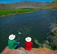 two people in cowboy hats looking at river